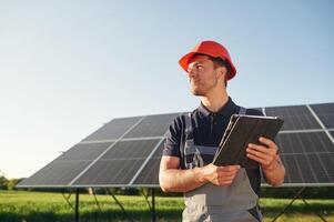 Summer, time, standing ,and holding digital tablet. Man is doing operating and maintenance in solar power plant photo