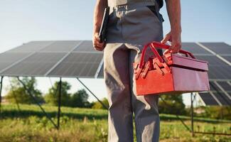 Walking ,and holding, repair toolbox. Close up view of man that is doing maintenance in solar power plant photo