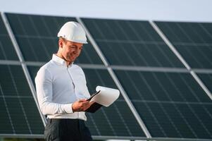 Notepad with document is, in, hands. Man is doing operating and maintenance in solar power plant photo