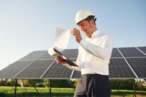 Notepad with ,document is in hands. Man is doing operating and maintenance in solar power plant photo