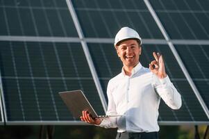 Modern, laptop is in hands. Man is doing ,operating and maintenance in solar power plant photo