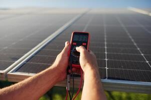 Holds ,a, thermal imager. Close up view of man that is doing operating and maintenance in solar power plant photo
