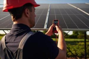 Measuring the electricity by ,using device. Man is doing operating and maintenance in solar power plant photo