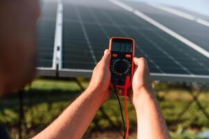 Measuring, the electricity, by using device. Man is doing operating and maintenance in solar power plant photo