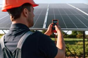 Measuring the, electricity by using device. Man is doing operating and maintenance in solar power plant photo