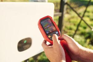 Holds a, thermal imager. Close up view of man that is doing operating and maintenance in solar power plant photo