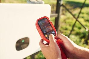 Holds a thermal imager.. Close up view of man that is doing operating and maintenance in solar power plant photo