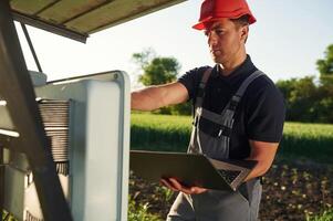 Maintenance by using ,,laptop. Man is doing operating solar power plant photo