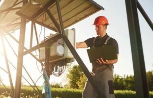 Maintenance by,, using laptop. Man is doing operating solar power plant photo