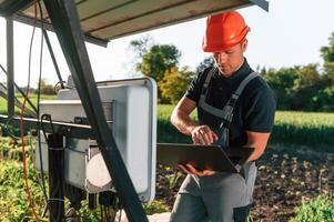 Maintenance, by using laptop. Man is doing operating solar power plant photo