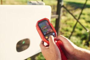 Holds, a thermal imager. Close up view of man that is doing operating and maintenance in solar power plant photo