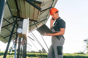 Maintenance by, using laptop. Man is doing operating solar power plant photo