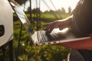 With, laptop in hands. Close up view of man that is doing operating and maintenance in solar power plant photo