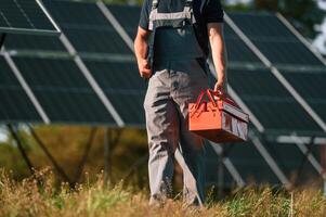 Walking ,and holding repair toolbox. Close up view of man that is doing maintenance in solar power plant photo