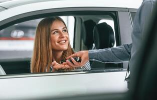 Giving the keys. Man in formal clothes is with woman customer with the electric car photo
