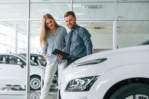 Helping the customer. Man ,in ,formal clothes is with woman with the electric car photo
