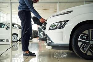 Putting charger into electrical car socket. Close up view of man photo