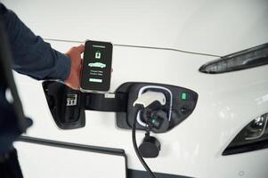 Charging process on the smartphone ,app. Close up view of man that is with electrical car photo
