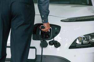 View from behind of man with charger ,of man that is with electrical car photo
