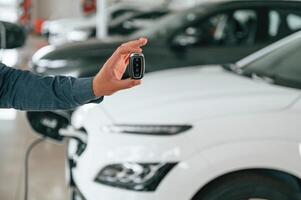 Hand is holding ,the keys. Close up ,view of man that is with electrical car photo