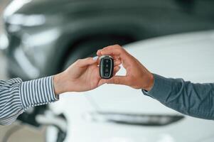 Close up view. Man, and woman hands are holding keys from the new automobile photo