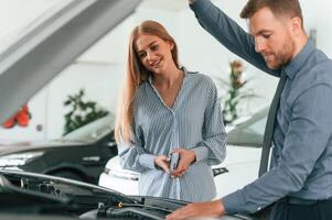 Man in formal clothes ,is with woman customer with the electric car photo
