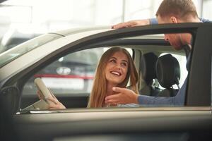 Man in ,formal ,clothes is with woman customer with the electric car photo