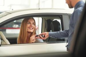 Giving ,the ,keys. Man in formal clothes is with woman customer with the electric car photo