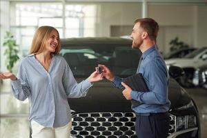 Giving, the, keys. Man in formal clothes is with woman customer with the electric car photo
