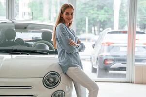 Cheerful beautiful woman is indoors with the modern car photo