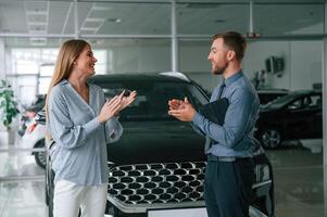 Buying ,the automobile,, taking keys. Man in formal clothes is with woman customer with the electric car photo