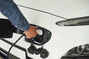 Putting ,charger into electrical car socket. Close up view of man photo