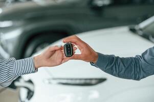 Close ,up view. Man and woman hands are holding keys from the new automobile photo