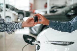 Man, in ,formal clothes is with woman customer with the electric car photo