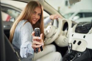 Showing ,the keys ,of new automobile. Beautiful woman is indoors with the modern car photo