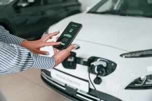 Conception ,of ,green energy. Smartphone with charging process data. Close up view of woman photo