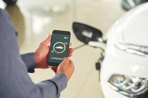 Charging ,process, on ,the smartphone app. Close up view of man that is with electrical car photo