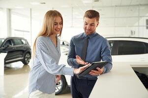 Information ,in the notepad. Man ,in formal clothes is with woman customer with the electric car photo
