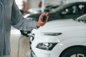 Hand, is ,holding the keys. Close up view of man that is with electrical car photo