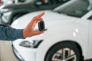 Hand is holding the keys. Close up view of man that is with electrical car photo