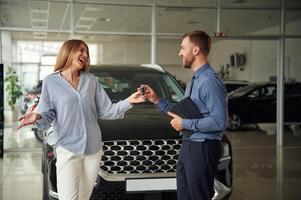 Buying ,the ,automobile, taking keys. Man in formal clothes is with woman customer with the electric car photo