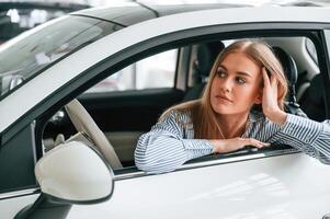 Leaning on the door with opened ,window. Beautiful woman is indoors with the modern car photo