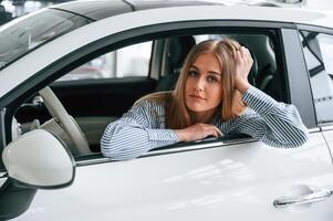 Leaning on, the, door with opened window. Beautiful woman is indoors with the modern car photo