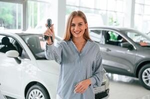 New owner o,f the car. With keys in hands. Beautiful woman is indoors photo