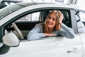 Leaning on, the door with opened window. Beautiful woman is indoors with the modern car photo