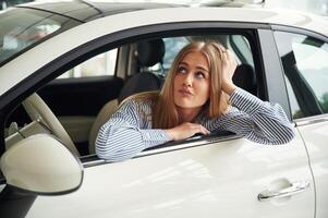 Leaning ,on the door with opened window. Beautiful woman is indoors with the modern car photo