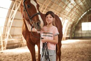 Portrait of ,cute little girl that is with, horse indoors photo