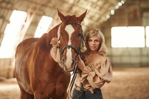 Front ,view. Beautiful ,young woman is with horse indoors photo