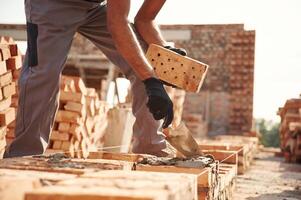 With brick in hands. Close up, view, of man that is working on the construction site photo