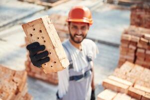 Close ,up, view ,of brick that ,is in the hands. Handsome Indian man is on the construction site photo